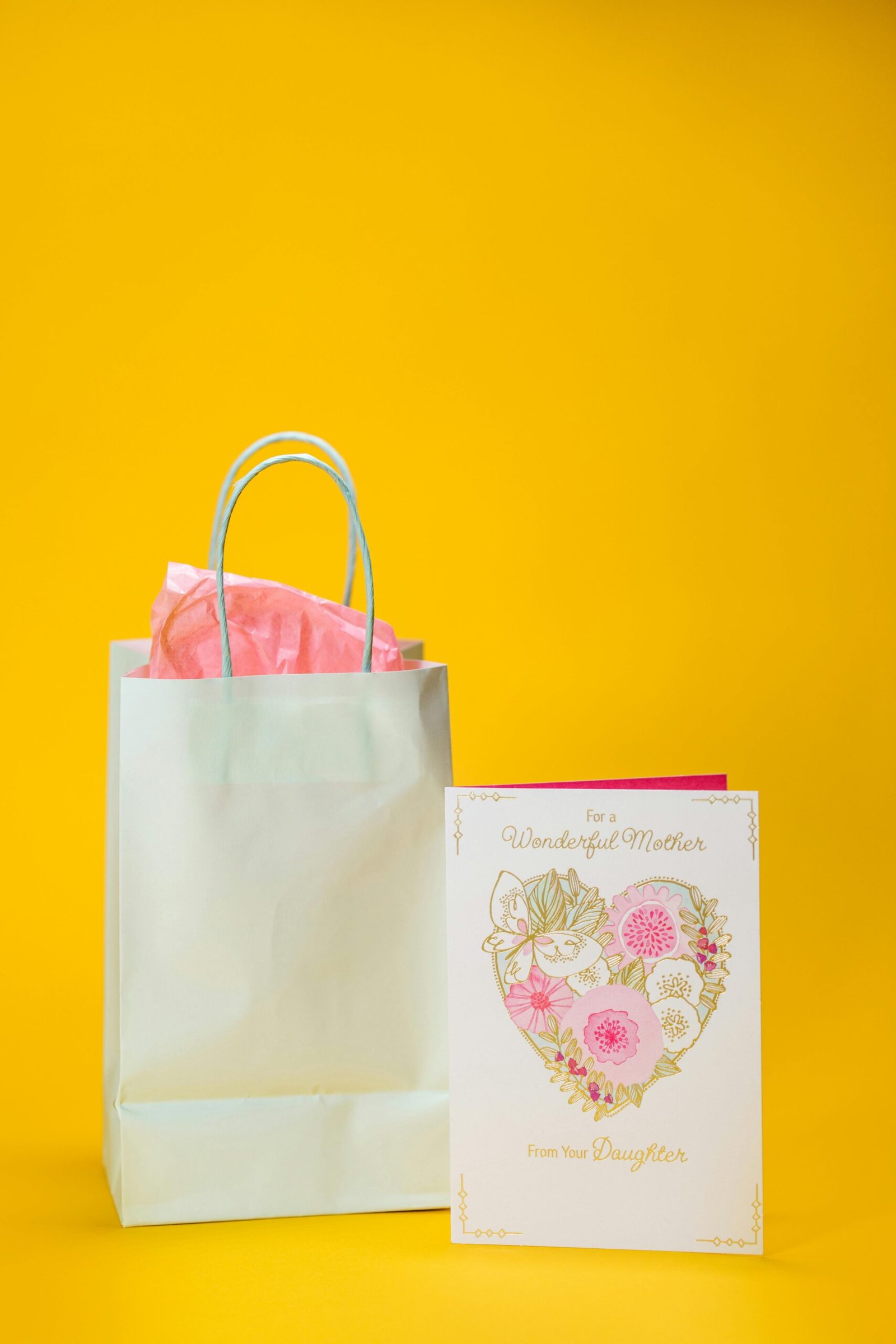 A gift bag and Mother's Day card on a vibrant yellow background, ideal for celebrations.